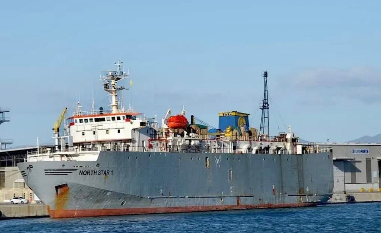 Large grey cargo ship "NORTH STAR 1" docked in a sunny port with blue water.