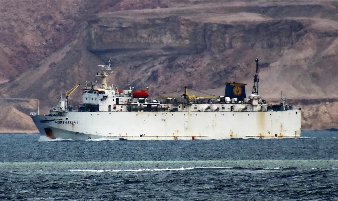 "NORTH STAR 1" cargo ship sailing on choppy water, barren mountains in background.